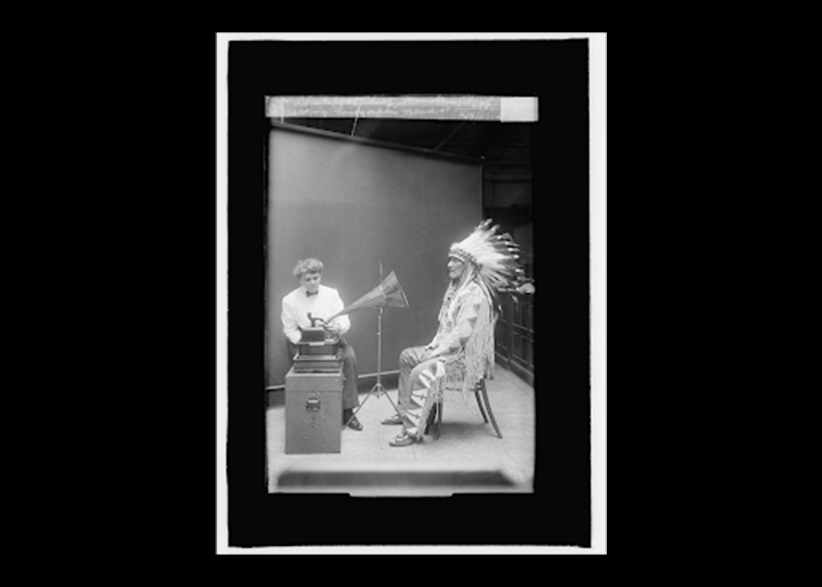 A historical, black and white photograph of ethnographer, Frances Densmore conducting an interview with Blackfoot leader, Mountain Chief. 